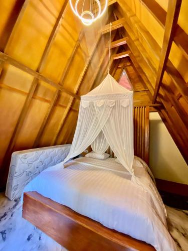 a bedroom with a white bed with a chandelier at Villa Marcelinus in Kelimutu