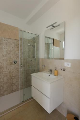 a bathroom with a white sink and a shower at Astro apartments with direct access on the sea of Noto heritage of Unesco in Noto