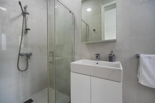a white bathroom with a sink and a shower at Sliema Seaside Apartment Retreat in Sliema