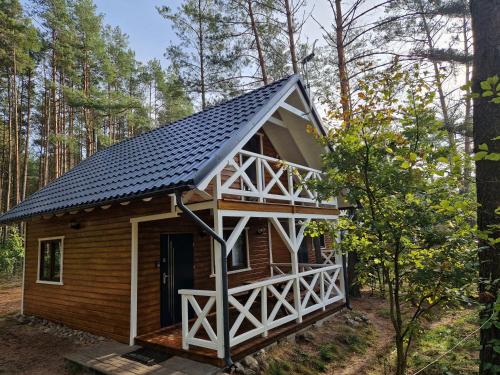 a cabin in the woods with a black roof at Leśny Domek Rotembark z prywatnym jacuzzi in Kościerzyna