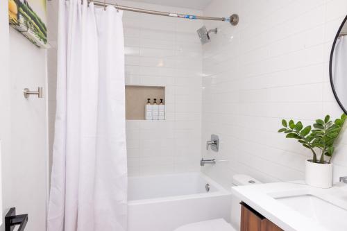 a white bathroom with a shower curtain and a sink at Luxe Retreat, Modern Gem with Private Backyard Oasis in Austin