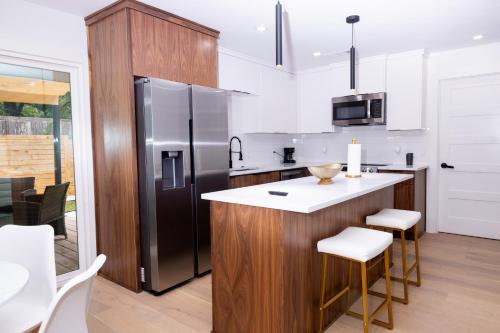 a kitchen with a refrigerator and a counter with stools at Luxe Retreat, Modern Gem with Private Backyard Oasis in Austin