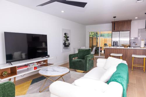a living room with a white couch and a tv at Luxe Retreat, Modern Gem with Private Backyard Oasis in Austin