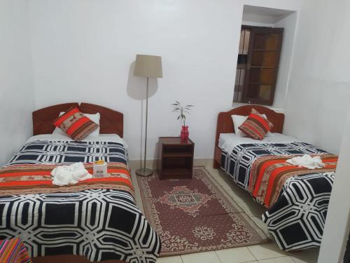 a bedroom with two beds and a rug at Hotel Kuelap Chachapoyas in Chachapoyas