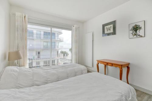 a white bedroom with two beds and a window at Pieds dans l'eau - Balcon vue mer in La Baule
