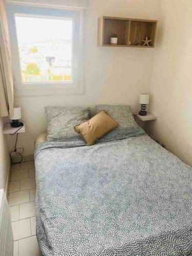 une chambre avec un lit avec une couette bleue et une fenêtre dans l'établissement Apt T2 cabine climatisé à 1 min mer, balcon, piscine, au Cap d'Agde