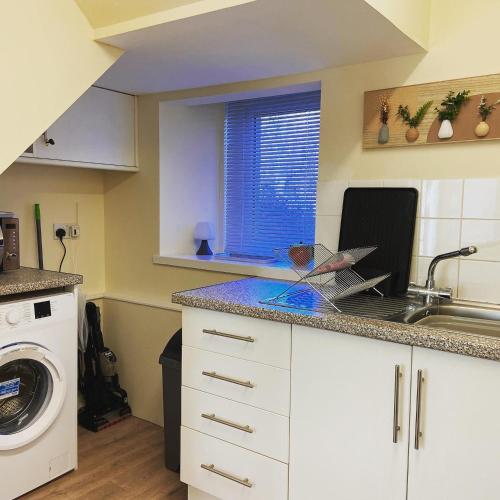 a kitchen with a sink and a washing machine at Dalvey Mill Cottage in Forres