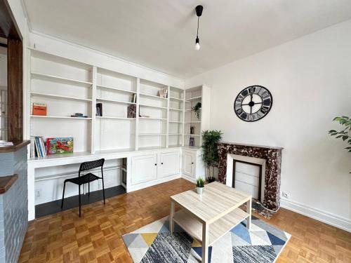 - un salon avec une table et une horloge murale dans l'établissement Détroit - Maison spacieuse et lumineuse pour 8 personnes, à Reims