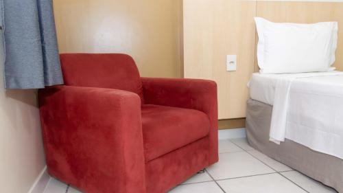 a red chair in a room with a bed at Hotel Vila Rica Belém in Belém