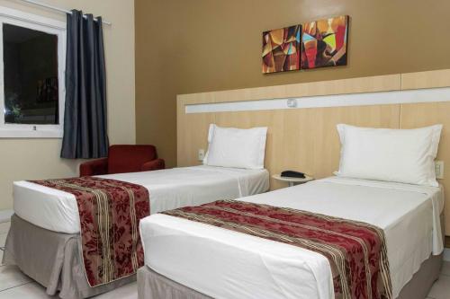 a hotel room with two beds and a chair at Hotel Vila Rica Belém in Belém