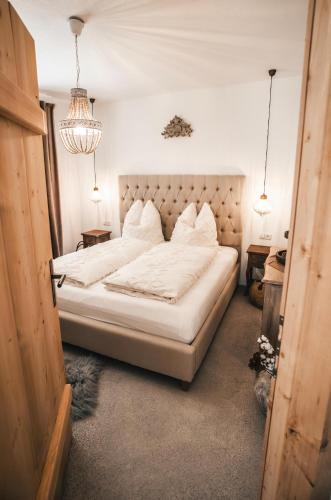 a bedroom with a bed with white sheets and pillows at K-Style Chalet Premium-Twin-Lofts with private Sauna in Mieders
