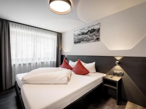 a hotel room with two beds with red pillows at The Black by Regina in Sölden