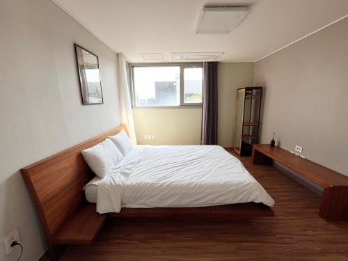 ソギポにあるJejumodo2 Outdoor Jacuzzi Detached Houseの白いシーツと窓のあるベッドのある寝室