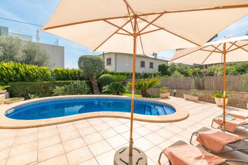 a patio with an umbrella and a swimming pool at Beach Villa Arran de Mar by Sealand Villas in Alcudia