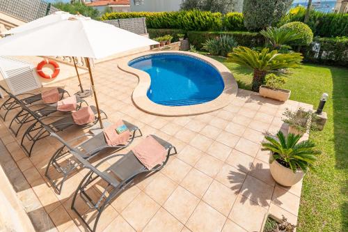 a patio with chairs and an umbrella and a swimming pool at Beach Villa Arran de Mar by Sealand Villas in Alcudia