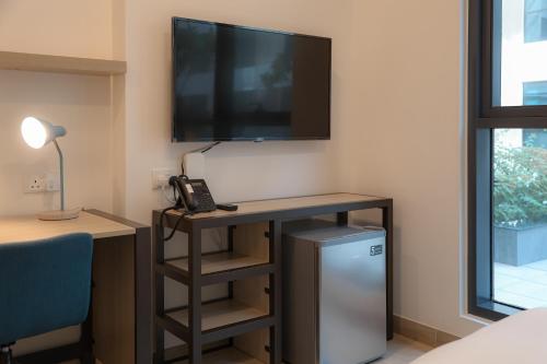 a room with a desk with a television and a phone at The Myriad Muscat - Female Only ذا ميرياد مسقط - للنساء فقط in Seeb