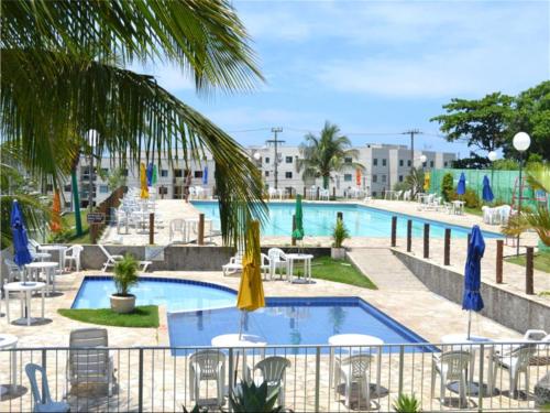 a pool with chairs and umbrellas in a resort at Apartamento Paraiso Litoral in São Pedro da Aldeia