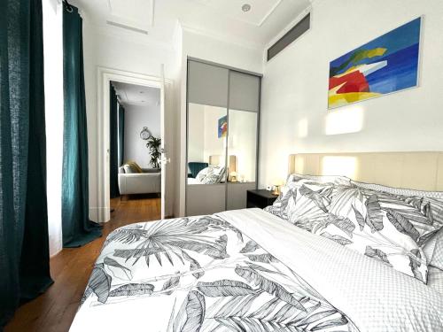 a bedroom with a white bed with a black and white comforter at Cœur Capitole 122m2- Clim - Parking - Ascenseur- Métro in Toulouse