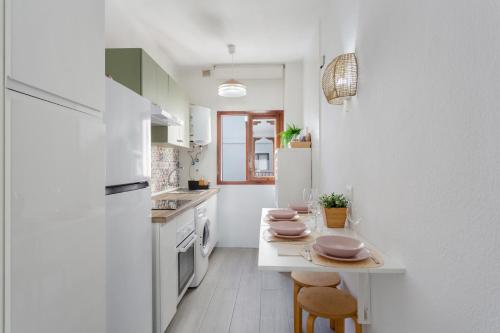 a kitchen with white cabinets and a table with stools at Martimar Candelaria in Candelaria