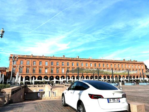 a white car parked in front of a large building at Cœur Capitole 122m2- Clim - Parking - Ascenseur- Métro in Toulouse