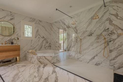 une salle de bain en marbre blanc avec une baignoire et un lavabo dans l'établissement La Villa Suarela, à Cavaillon