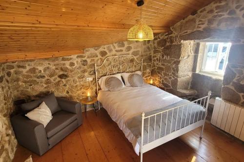 a bedroom with a bed and a chair in a stone wall at O lar de Cabanas in Brion