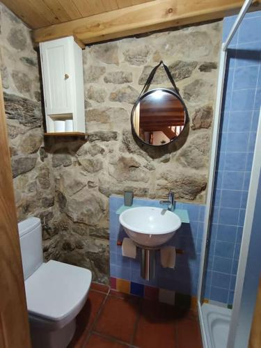 a stone bathroom with a sink and a toilet at O lar de Cabanas in Brion