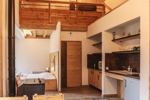 a bedroom with a bed and a kitchen with wooden cabinets at Village de gîtes de Sainte-Lucie in Sainte-Lucie