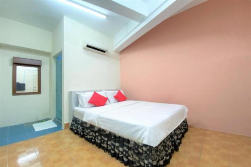 a bedroom with a white bed with red pillows at B Hotel Penang in George Town