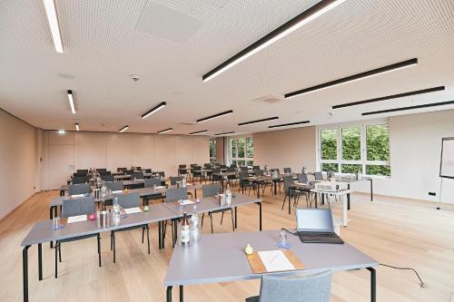 a large room with tables and chairs and a screen at Seehotel Maria Laach in Maria Laach
