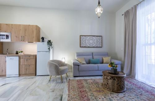 Una sala de estar con un sofá azul y una cocina. en Alcazar Centrico Moderno, en Jerez de la Frontera