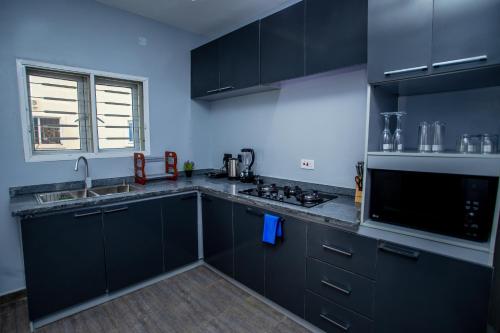 a kitchen with black cabinets and a sink at Aija Residences in Abuja