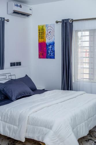 a bedroom with a white bed and a painting on the wall at Aija Residences in Abuja