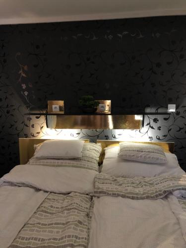 a bed with a wooden headboard with two pillows at Gavriel Boutique Residence Wellness Spa in Szada