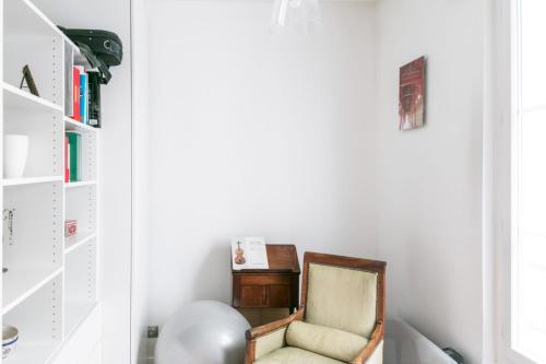 une chambre avec une chaise et une étagère dans l'établissement Appartement Pontiac - Welkeys, à Paris