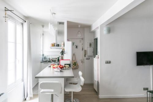 une cuisine blanche avec une table et des chaises blanches dans l'établissement Appartement Pontiac - Welkeys, à Paris