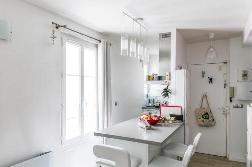 une cuisine blanche avec une table et des chaises blanches dans l'établissement Appartement Pontiac - Welkeys, à Paris