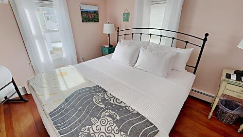 un letto con lenzuola e cuscini bianchi in una camera da letto di Lobster Cottage a Prospect Harbor