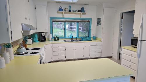 a kitchen with white cabinets and a sink and a window at Serenity By the Sea in Sorrento