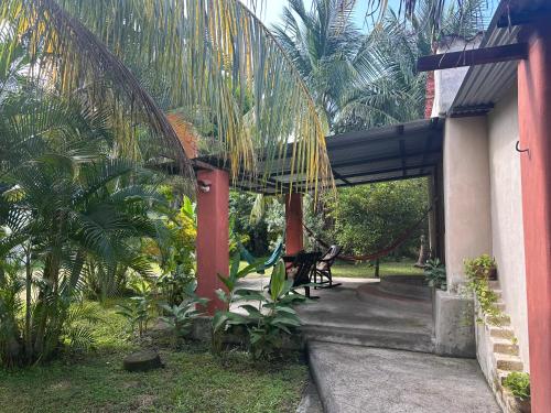 a porch of a house with a hammock and palm trees at Rancho Tranquillo in Moyogalpa
