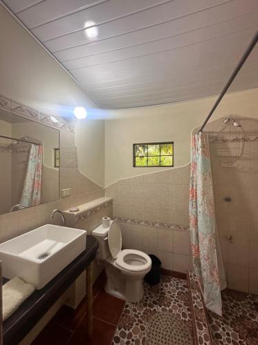 a bathroom with a sink and a toilet and a mirror at Rancho Tranquillo in Moyogalpa