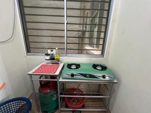 a table with a stove in a room with a window at Sandakan Homestay & Backpackers in Sandakan