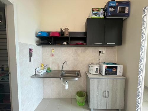 a small kitchen with a sink and a microwave at Sandakan Homestay & Backpackers in Sandakan