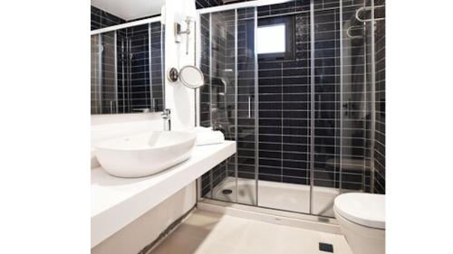 a black tiled bathroom with a sink and a toilet at Casa Mimosa Hotel in Karaburun