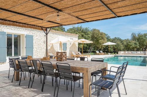 une terrasse avec une table et des chaises en bois ainsi qu'une piscine dans l'établissement La Bohème, à Bonnieux