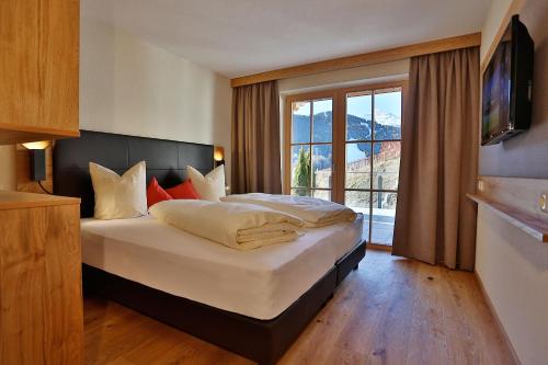 ein Schlafzimmer mit einem großen Bett mit einem großen Fenster in der Unterkunft Noldis Apart in Serfaus