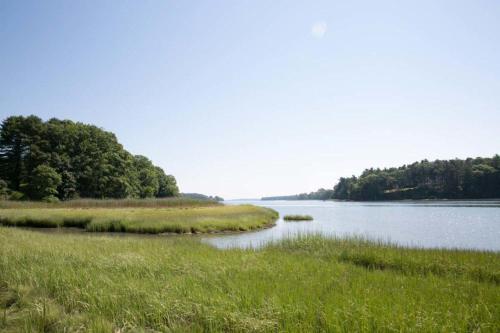 a body of water with green grass and trees at Sparrowhawk House in Yarmouth
