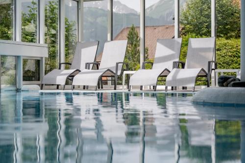 a row of white chairs next to a swimming pool at Wellness & Sporthotel Alpenhof in Ehrwald