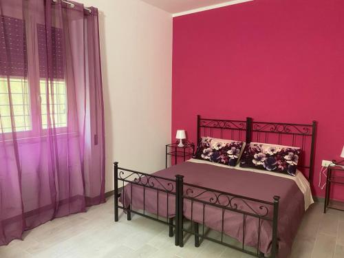 a bedroom with pink walls and a bed with pillows at B&B Sole e Luna in Ponte Galeria
