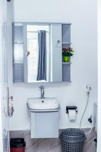 a white bathroom with a sink and a mirror at Aija Residences in Abuja